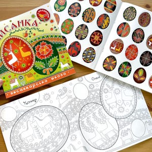 Op de afbeelding: Een kleurrijk boek getiteld "Pysanka - Mijn Kunstboek" met een traditioneel Oekraïens paasei-ontwerp op de omslag. Het boek bevat een set stickers met verschillende ei-ontwerpen en een kleurboek met contouren van eieren om in te kleuren.
