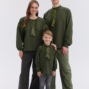 May include: Three people wearing matching olive green shirts with embroidered details and tassels. The shirts have long sleeves and are paired with dark pants. The text "Create Your Matching Family Look" is at the top of the image.