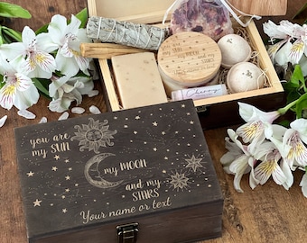 May include: A wooden box with a lid engraved with the text "You are my sun, my moon and my stars." The box is filled with bath products, including a bar of soap, bath bombs, and a small bottle of lotion. The box is a great gift for someone special.