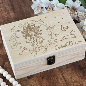 May include: A wooden box with a hinged lid and a latch. The box is engraved with a zodiac sign, the constellation Leo, and the name "Sarah Brown".