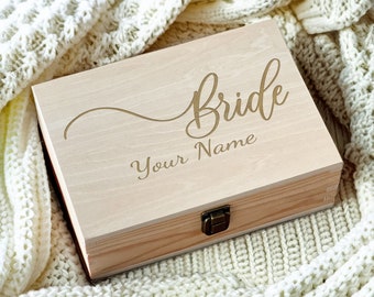 May include: A wooden box with a hinged lid and a brass latch. The box is engraved with the word "bride" in a cursive font and the text "Your Name".