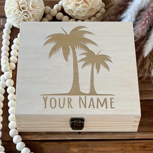 May include: A wooden box with a hinged lid and a brass latch. The box is decorated with an engraved design of two palm trees and the text "YOUR NAME".
