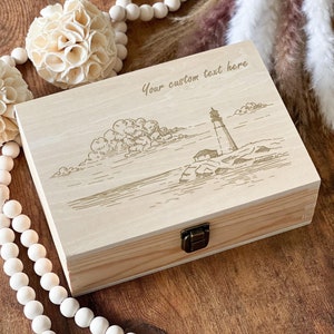 May include: A wooden box with a hinged lid and a brass latch. The box is engraved with a lighthouse scene and the text "Your custom text here".