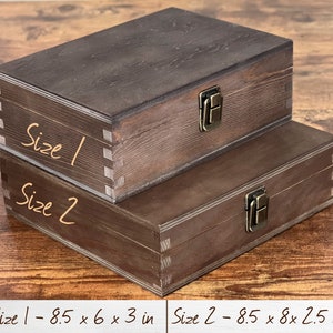 May include: Two wooden boxes with brass clasps. The smaller box is labeled "Size 1 - 8.5 x 6 x 3 in" and the larger box is labeled "Size 2 - 8.5 x 8 x 2.5 in".