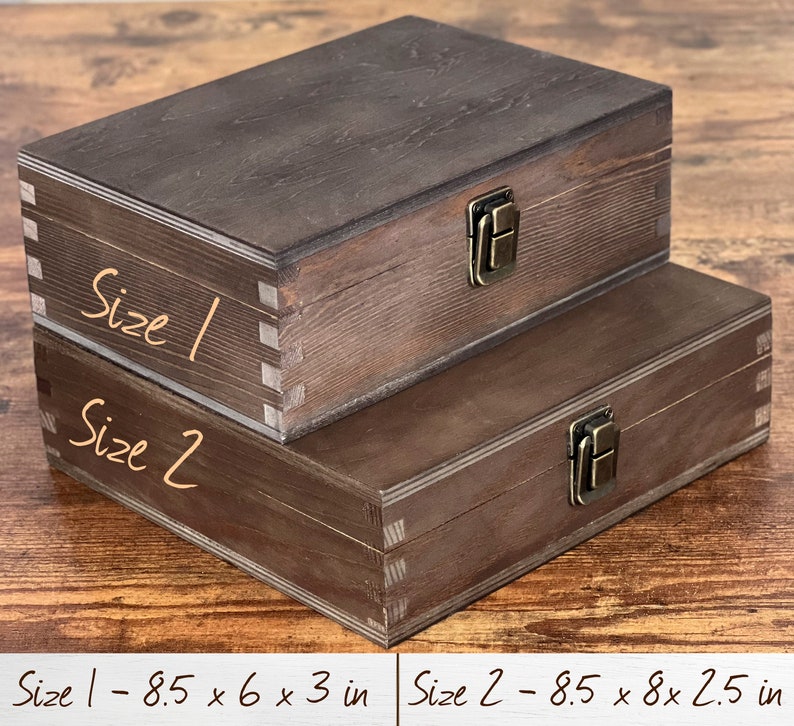 May include: Two wooden boxes with brass clasps. The smaller box is labeled "Size 1 - 8.5 x 6 x 3 in" and the larger box is labeled "Size 2 - 8.5 x 8 x 2.5 in".