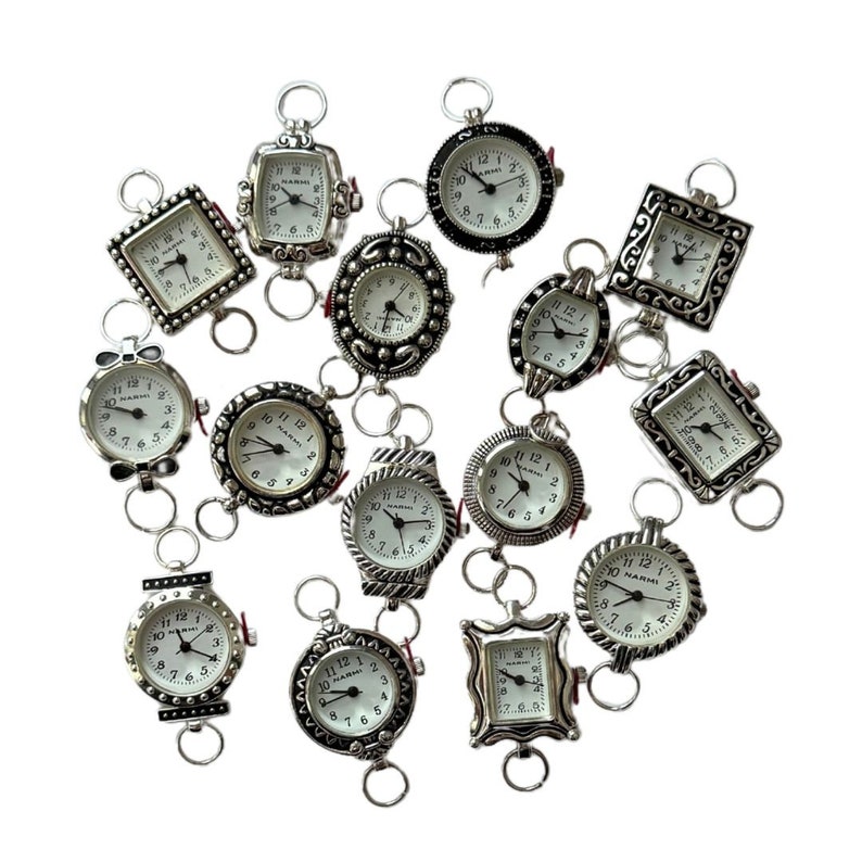 May include: A collection of 14 silver-toned pocket watches with white faces and black Roman numeral hour markers. The watches have different decorative frames and are connected by silver chains.