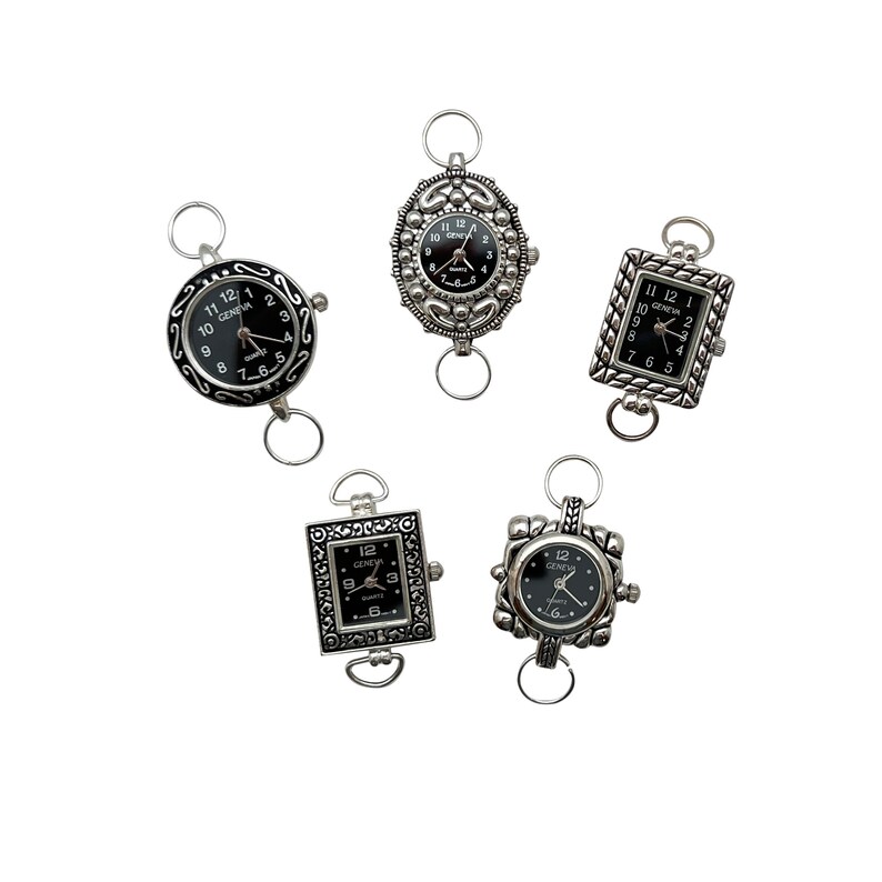 May include: Five silver-toned watch charms with black watch faces. The watch faces have black Roman numeral hour markers and black hands. The charms have different decorative designs around the watch faces.