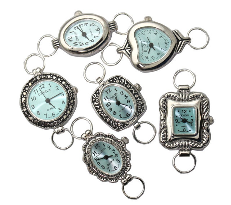 May include: Six silver-toned pocket watches with different designs and blue faces. The watches have a loop on the top for attaching to a chain or bracelet. The watches have Roman numeral markings and say "GENEVA" and "QUARTZ" on the face.