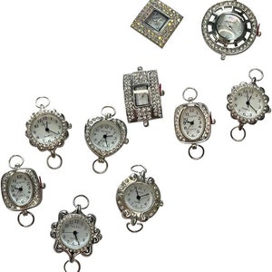 May include: Assortment of ten silver-toned watch faces with rhinestones. The watch faces are in various shapes, including round, square, oval, and rectangular. Some of the watch faces have the word "Quartz" printed on them.