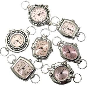 May include: Seven silver-toned pocket watches with pink faces and black hands. The watches have different shapes and designs, including round, square, and oval. Each watch has a loop at the top for attaching to a chain or bracelet.