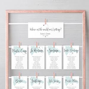 Könnte beinhalten: Ein Sitzplan für eine Hochzeit mit einem Reise-Thema. Der Plan wird auf einem roségoldenen Rahmen mit Karten angezeigt, die an Wäscheklammern hängen. Jede Karte zeigt den Namen einer anderen Stadt und eine kleine Karte der Stadt. Der Text oben auf dem Plan lautet "Wo bin ich in der Welt?" gefolgt von den Namen "Sam & Jane".