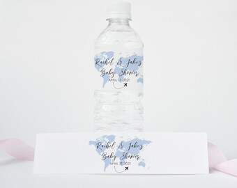 May include: A clear plastic water bottle with a white cap and a label featuring a light blue world map design. The label reads "Rachel & Jake's Baby Shower APRIL 12 2021" with a small airplane graphic. A matching label is below.