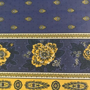 May include: A patterned fabric featuring a navy blue background with yellow floral and geometric designs. The fabric has a repeating pattern of yellow flowers and small, ornate yellow and blue shapes.