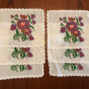 May include: Set of six white crocheted placemats with embroidered floral designs in shades of purple, green, and red.