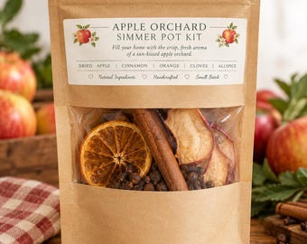 May include: A brown kraft paper pouch containing an Apple Orchard Simmer Pot Kit. The label reads: APPLE ORCHARD SIMMER POT KIT, Fill your home with the crisp, fresh aroma of a sun-kissed apple orchard. DRIED APPLE | CINNAMON | ORANGE | CLOVES | ALLSPICE.