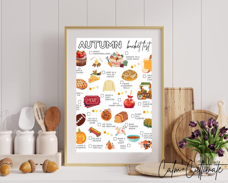 May include: A framed autumn bucket list print with a gold frame. The list includes activities like apple picking, eating candy apples, and visiting a pumpkin patch. The print has a white background with colorful illustrations and the text "Autumn Bucket List".