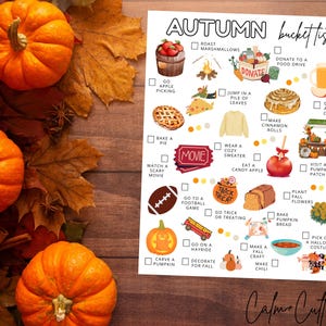 May include: An autumn-themed bucket list with illustrations and text, including pumpkins, leaves, and fall activities. The list includes activities like apple picking, baking a pie, and visiting a pumpkin patch. The words "AUTUMN bucket list" are at the top.