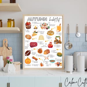 May include: A framed "Autumn Bucket List" print with a light wood frame. The list includes fall activities like apple picking, baking pie, and carving pumpkins. The print is displayed in a kitchen setting with jars and utensils.