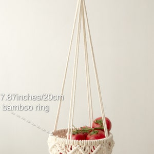 Elegant cream-colored macrame one-tier fruit basket, with dimensions labeled, showcasing vegetables in a bright, natural setting. Handmade craftsmanship by Macramebeautiful