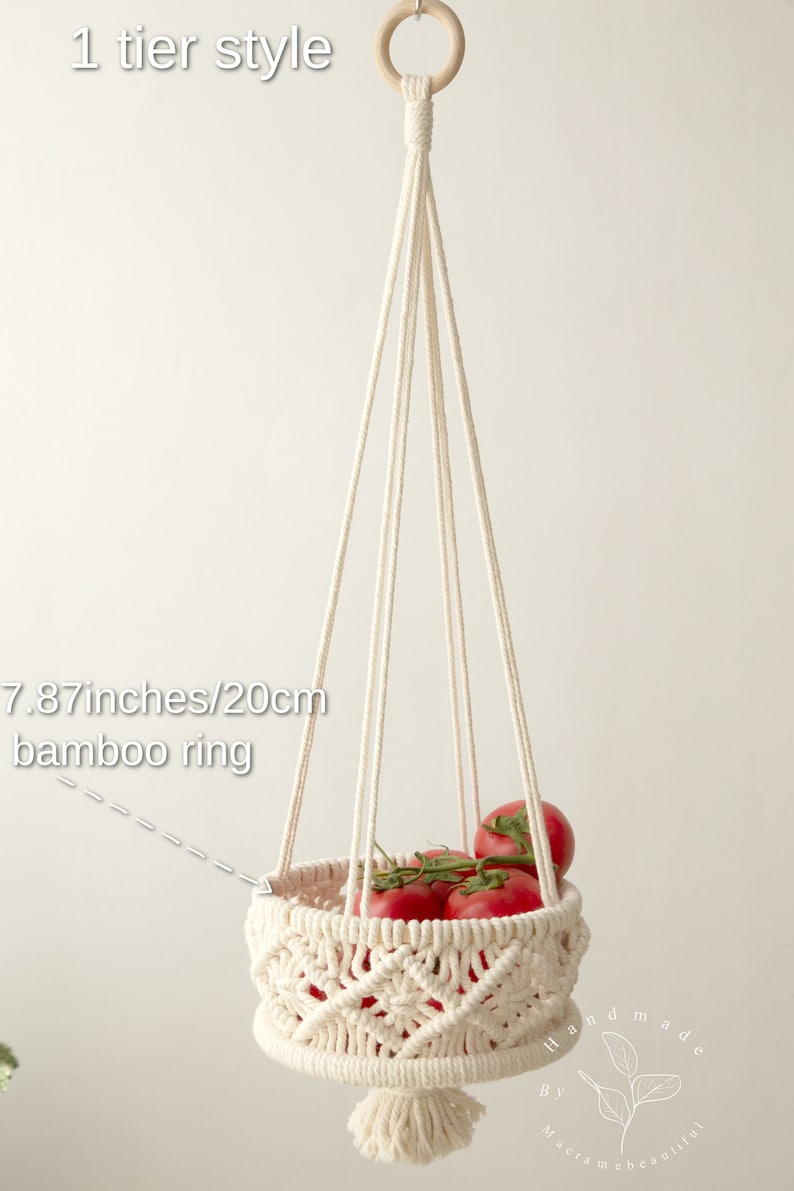 Elegant cream-colored macrame one-tier fruit basket, with dimensions labeled, showcasing vegetables in a bright, natural setting. Handmade craftsmanship by Macramebeautiful