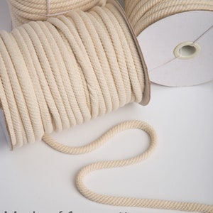 May include: Three spools of natural cotton rope, each 1 cm thick. The rope is wound around cardboard spools. The rope is made of natural cotton and is perfect for hanging plants or other heavy objects.