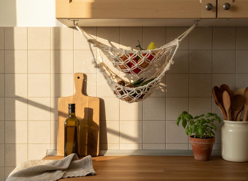 Handmade macramé two-tier fruit hammock in natural cotton, hanging kitchen fruit basket with apples, oranges and kiwis — boho farmhouse decor, space-saving organizer for countertop or wall.