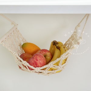 A close-up of a macrame fruit hammock cradling a vibrant selection of tomatoes and mushrooms, featuring intricate knotting patterns, perfect for a minimalist kitchen aesthetic