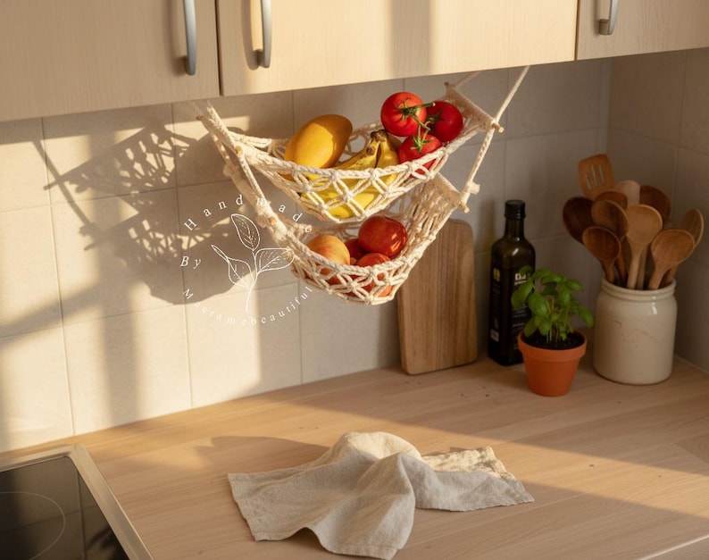 Handmade macramé two-tier fruit hammock in natural cotton, hanging kitchen fruit basket with apples, oranges and kiwis — boho farmhouse decor, space-saving organizer for countertop or wall.