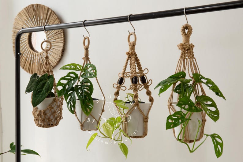 Handcrafted jute macramé plant hangers with wooden rings, featuring four distinct knot patterns suspending white ceramic pots filled with lush green pothos and monstera vines—boho-chic indoor décor perfect for hanging planters, windowsills, balconies.