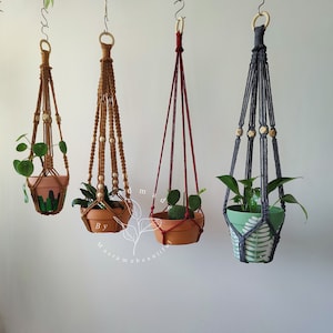 Assorted macrame plant hangers featuring various knotting styles in shades of Cinnamon, red, and gray, created by Macramebeautiful, with intricate beadwork for stylish plant display