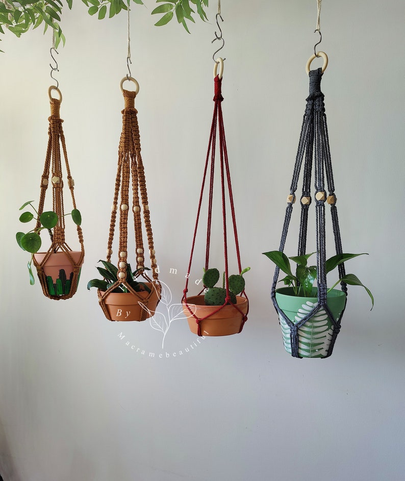 Assorted macrame plant hangers featuring various knotting styles in shades of Cinnamon, red, and gray, created by Macramebeautiful, with intricate beadwork for stylish plant display