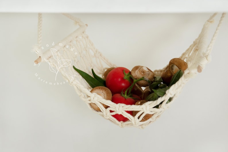 A close-up of a macrame fruit hammock cradling a vibrant selection of tomatoes and mushrooms, featuring intricate knotting patterns, perfect for a minimalist kitchen aesthetic