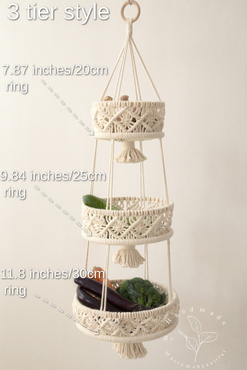 Elegant cream-colored macrame three-tier fruit basket, with dimensions labeled, showcasing vegetables in a bright, natural setting. Handmade craftsmanship by Macramebeautiful