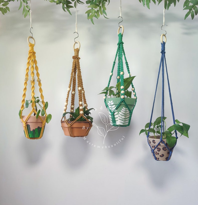 Vibrant collection of macrame plant hangers in yellow, Cinnamon, Green, and Navy blue, created by Macramebeautiful, each adorned with wooden beads, adding a pop of color to interior spaces