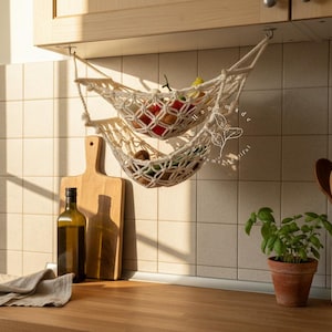 Handmade macramé two-tier fruit hammock in natural cotton, hanging kitchen fruit basket with apples, oranges and kiwis — boho farmhouse decor, space-saving organizer for countertop or wall.