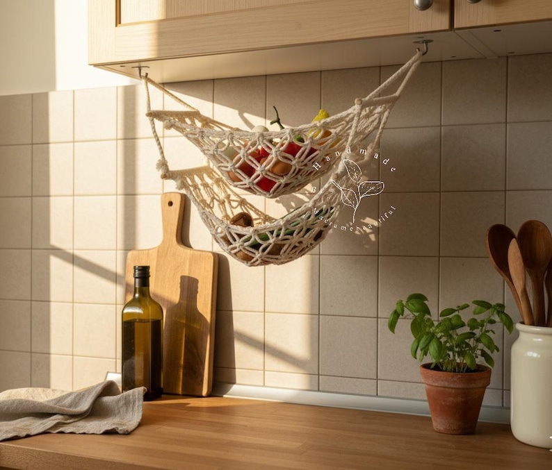 Handmade macramé two-tier fruit hammock in natural cotton, hanging kitchen fruit basket with apples, oranges and kiwis — boho farmhouse decor, space-saving organizer for countertop or wall.