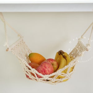 A close-up of a macrame fruit hammock cradling a vibrant selection of tomatoes and mushrooms, featuring intricate knotting patterns, perfect for a minimalist kitchen aesthetic