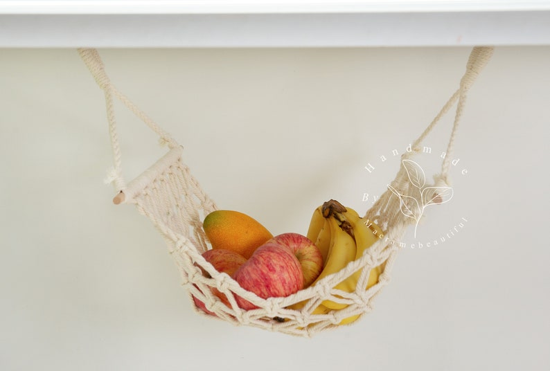 A close-up of a macrame fruit hammock cradling a vibrant selection of tomatoes and mushrooms, featuring intricate knotting patterns, perfect for a minimalist kitchen aesthetic