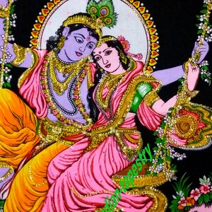 K&ouml;nnte beinhalten: Eine farbenfrohe Wandteppich, die ein Paar auf einer Schaukel zeigt. Der Mann ist blau mit goldenen Akzenten und die Frau tr&auml;gt ein rosa und gr&uuml;nes Kleid. Der Hintergrund ist schwarz mit floralen Akzenten.