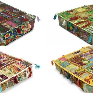 May include: Four square floor cushions featuring patchwork designs with intricate embroidery, beadwork, and small fabric tassels at each corner. The cushions display varied color palettes including deep greens, vibrant yellows, and multicolored patterns.