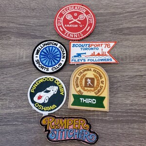 Peut inclure: Un ensemble de sept patchs brodés. Les patchs sont de formes et de tailles variées et présentent différents motifs, notamment une raquette de tennis, une silhouette de coureur, une voiture et un bateau. Les patchs sont tous de couleurs vives et ont un aspect vintage.
