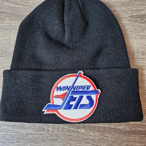 May include: Black knit beanie with a red, white, and blue Winnipeg Jets logo patch.