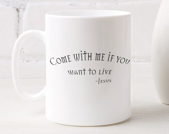 May include: White ceramic mug with a black inscription that reads "COME WITH ME IF YOU WANT TO LIVE -JESUS". The mug is sitting on a white wooden surface with a white vase and yellow flowers in the background.