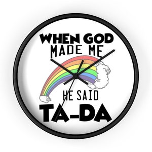 May include: A black and white wall clock with a rainbow and clouds graphic. The clock reads "When God Made Me He Said Ta-Da".