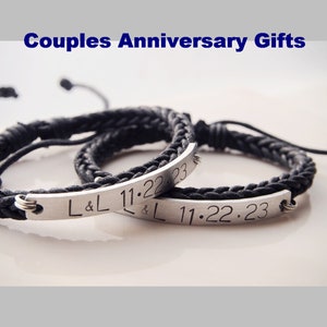 May include: A pair of black braided bracelets with silver metal plates engraved with "L&L 11.22.23".