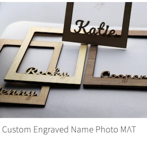 Könnte beinhalten: Eine Sammlung quadratischer Foto-Passepartouts aus Holz mit lasergeschnittenen Namen in Schreibschrift. Die Rahmen sind in hellen und dunklen Holztönen gehalten, wobei die Namen Katie, Rocky, Cooper und Penny deutlich zu sehen sind.