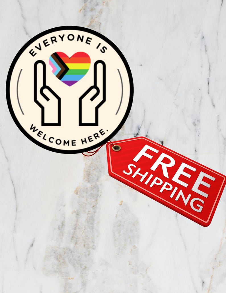 May include: A circular sticker with a cream background featuring a black line drawing of two hands cupping a multicoloured heart with the text EVERYONE IS WELCOME HERE. A red rectangular tag is attached to the side of the circular sticker.
