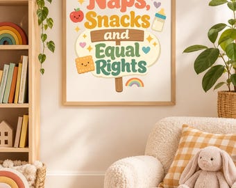 May include: A framed wall art print featuring the text Naps, Snacks and Equal Rights in colourful retro typography. The design includes illustrations of a red apple, a baby bottle, a smiling square cracker, small hearts, stars, and a rainbow.