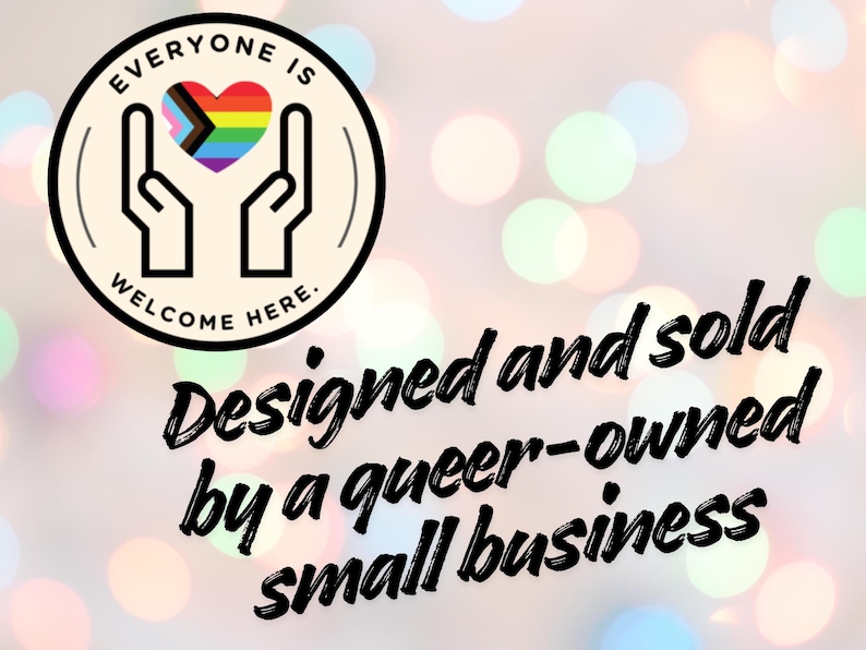 May include: A circular logo featuring two hands cupping a heart with the Progress Pride flag colours, surrounded by the text "EVERYONE IS WELCOME HERE." Below the logo, black text reads "Designed and sold by a queer-owned small business."