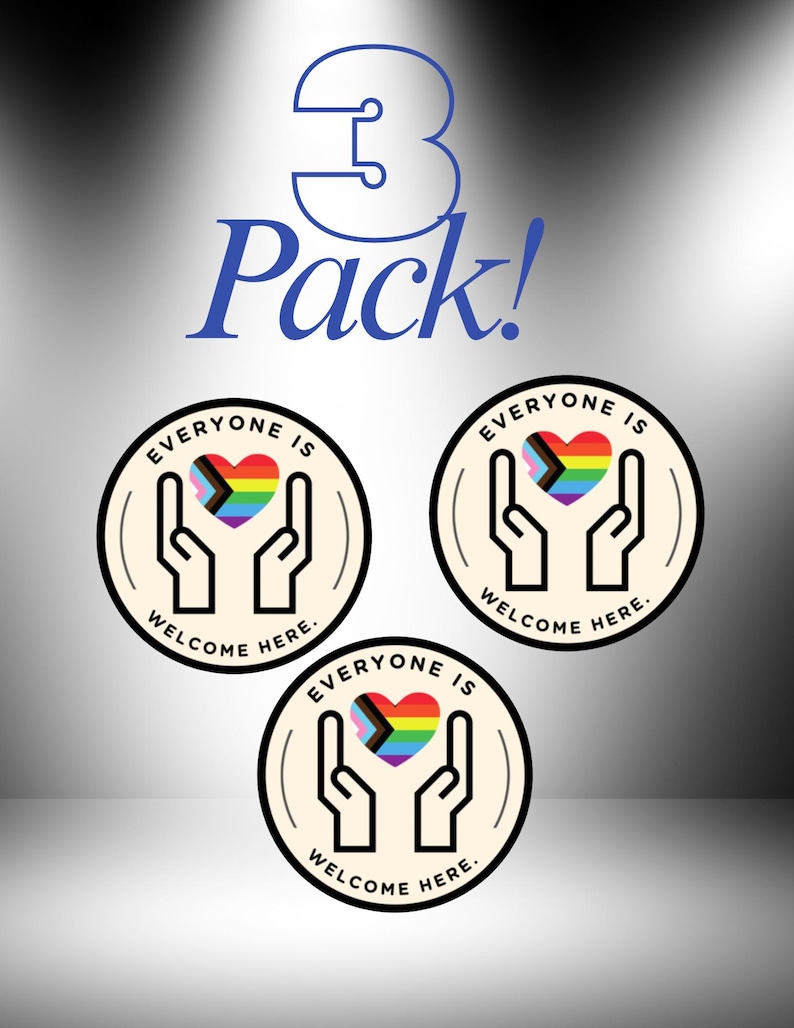 May include: A 3 Pack of circular stickers featuring a cream background with a black outline of two hands cupping a rainbow-coloured heart. The text "EVERYONE IS WELCOME HERE." is printed in black around the top and bottom of the sticker design.